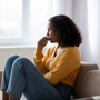 Mental health care. Depressed young black woman suffering from emotional burnout on couch at home