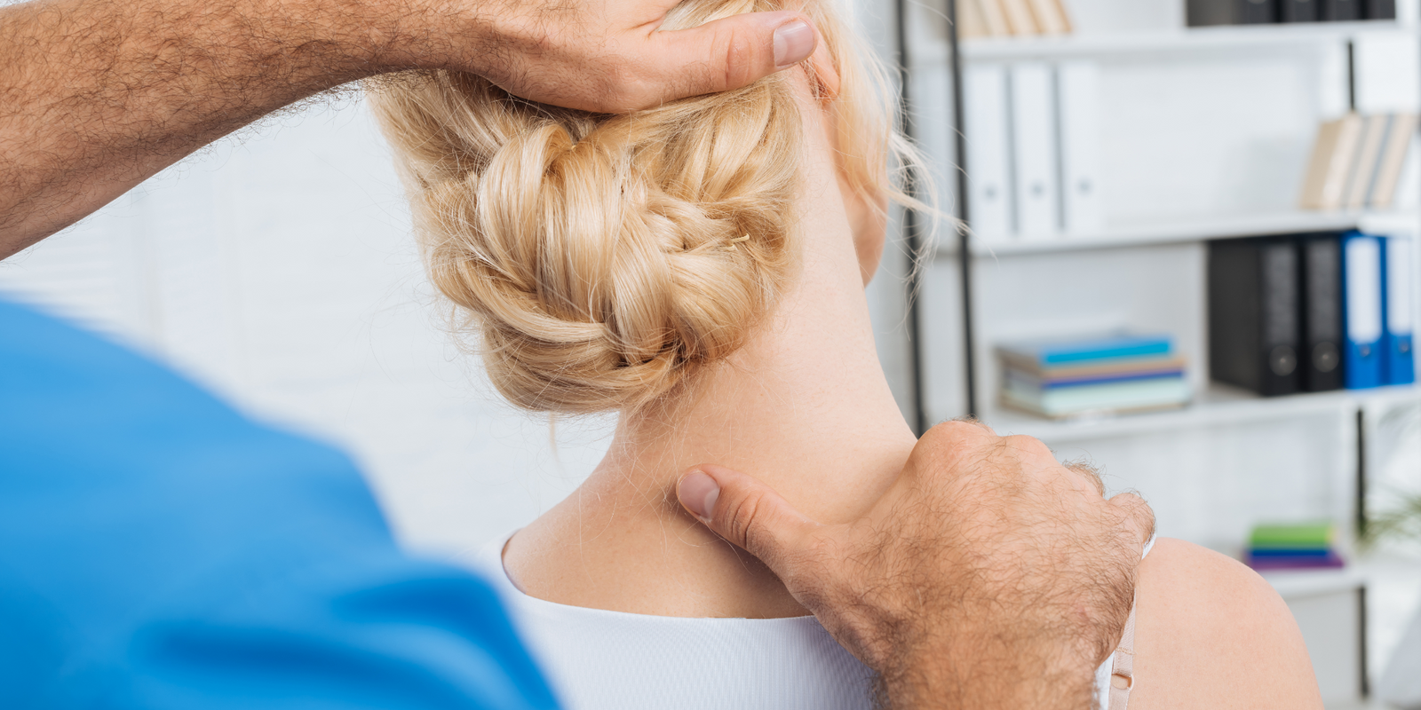 partial view of chiropractor stretching neck of woman during appointment in hospital