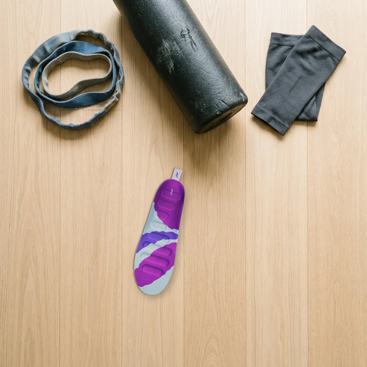 A RegenRx insole on the floor, apart from the resistance band, foam roller and calf sleeve already set aside.