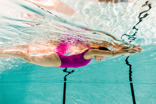 woman swimming underwater in swimming pool with blue water