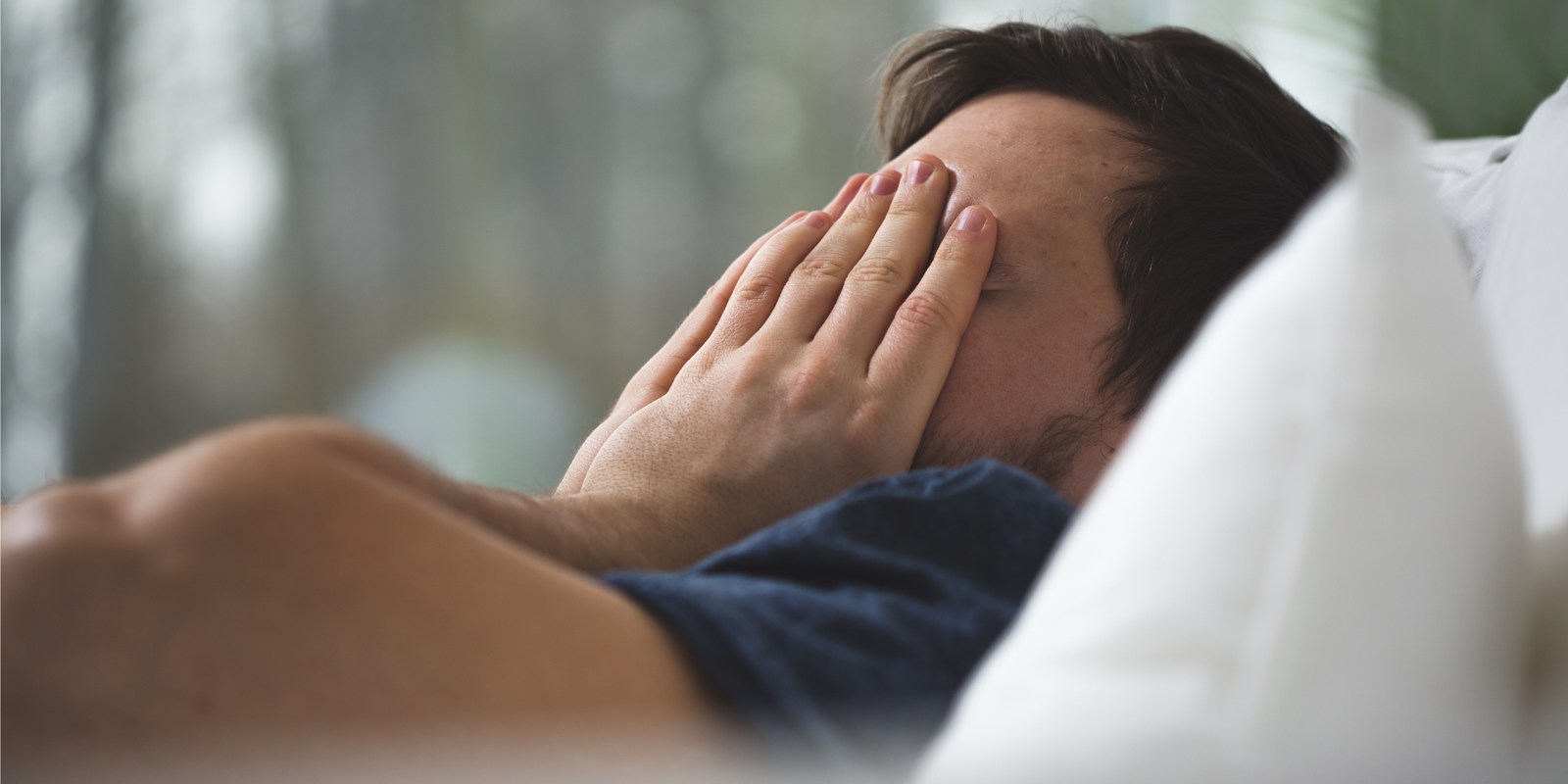 Young man with insomnia lying in bed and trying to sleep