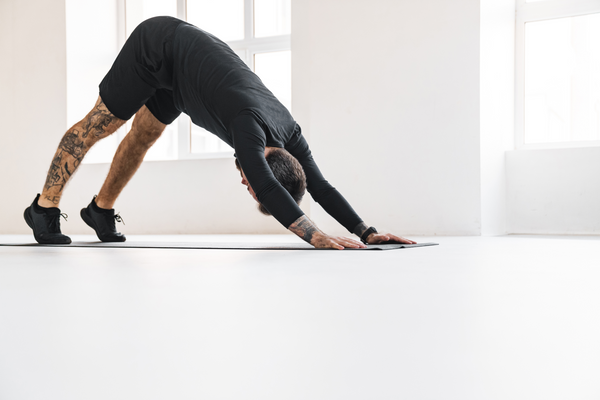 Bearded sportsman with tattoo doing exercise during yoga practice indoors