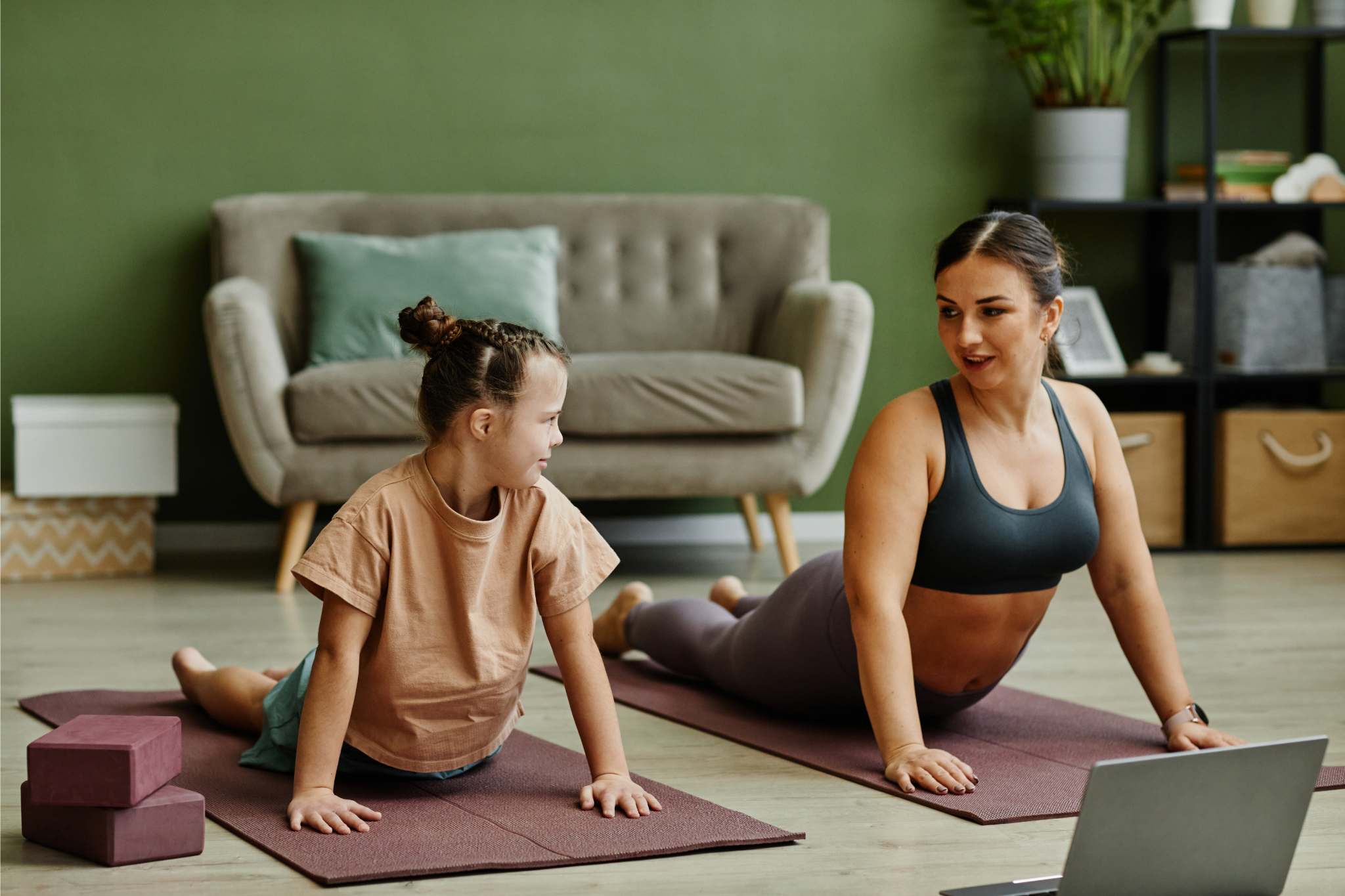 Portrait of young girl with down syndrome enjoying home workout with female instructor assisting