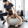 woman exercising in yoga ball with instructor injury rehabilitation 