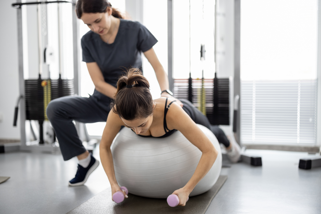 woman exercising in yoga ball with instructor injury rehabilitation 
