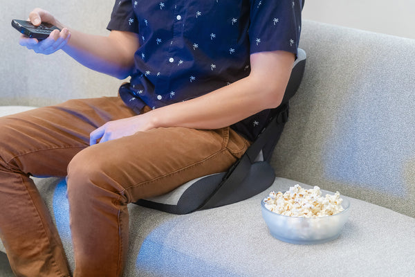 men sitting on a couch watching tv and eating popcorn, back pain cushion
