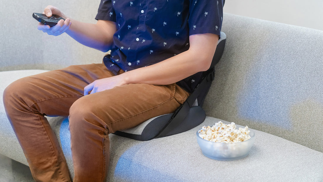 men sitting on a couch watching tv and eating popcorn, back pain cushion