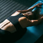 Beautiful young woman working out in gym, doing forward bend yoga exercise on blue mat, close-up