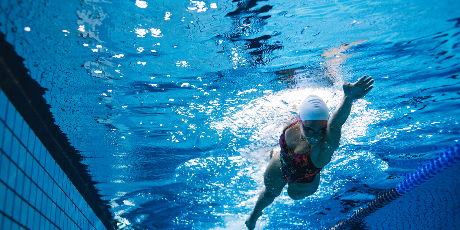 Underwater shot of young woman swimming the front crawl in pool. Fit female athlete swimming in pool.