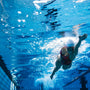 Underwater shot of young woman swimming the front crawl in pool. Fit female athlete swimming in pool.