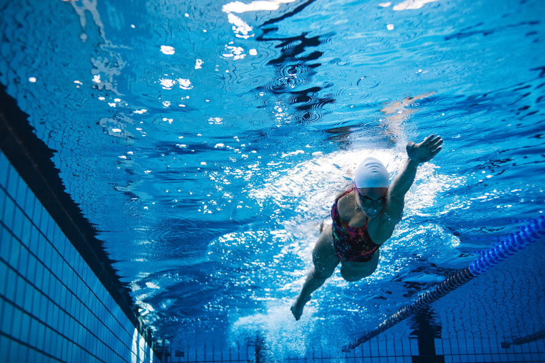 Underwater shot of young woman swimming the front crawl in pool. Fit female athlete swimming in pool.
