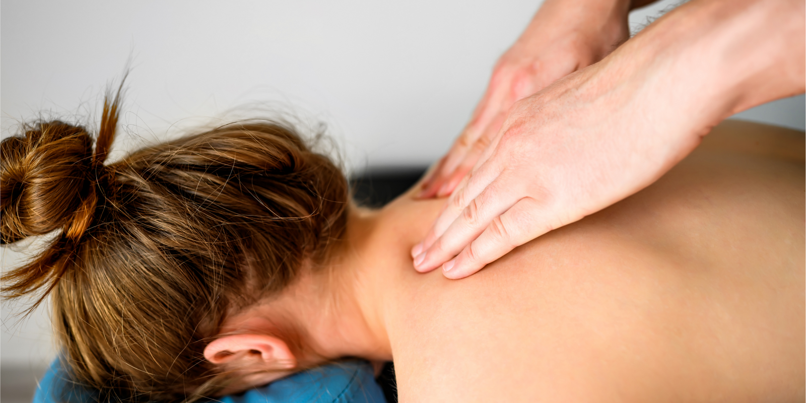 Girl during neck and shoulders massage in spa salon. Masseur hands doing care body therapy procedure for young woman wellness and relaxation.