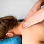 Girl during neck and shoulders massage in spa salon. Masseur hands doing care body therapy procedure for young woman wellness and relaxation.