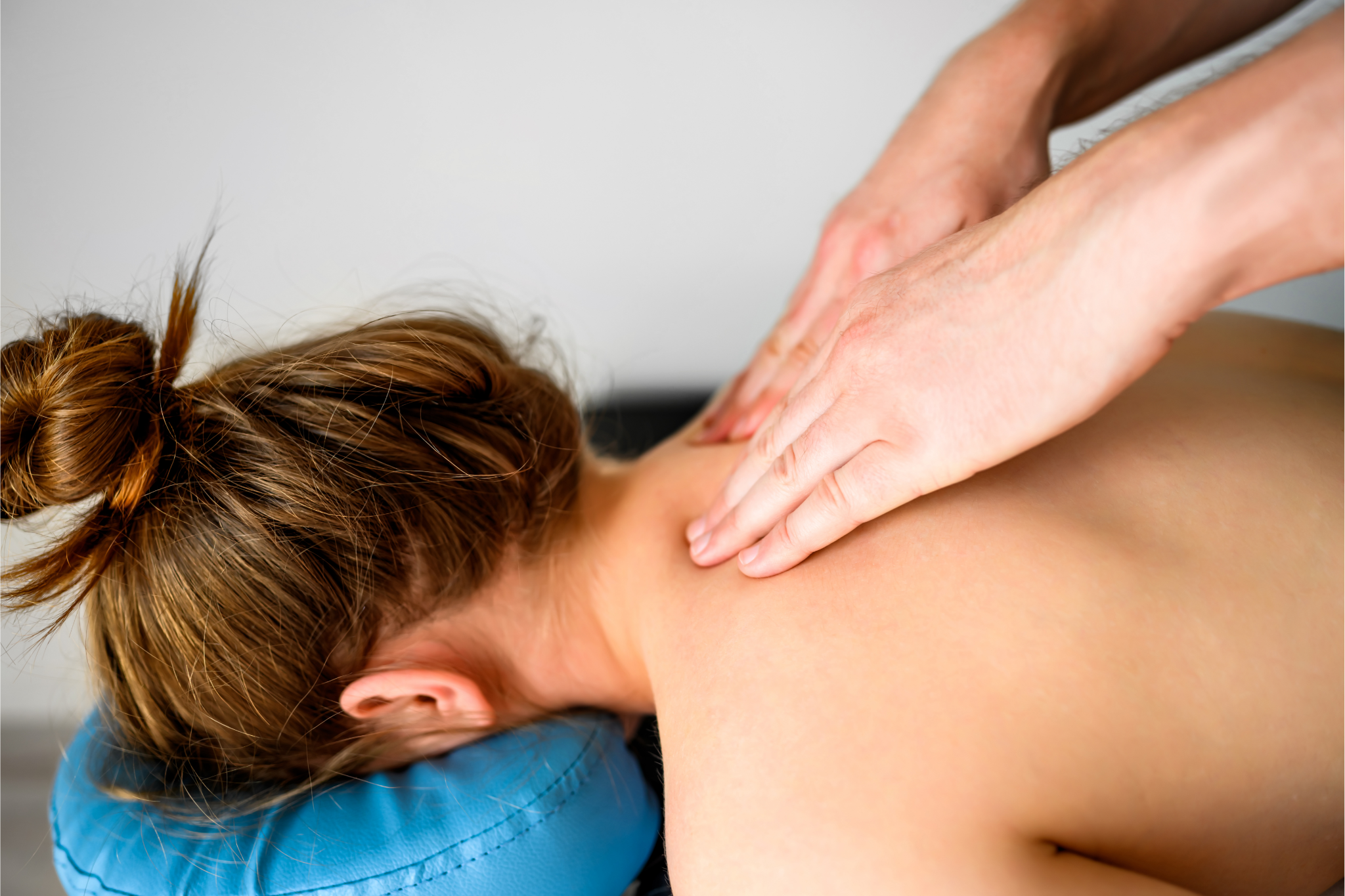 Girl during neck and shoulders massage in spa salon. Masseur hands doing care body therapy procedure for young woman wellness and relaxation.