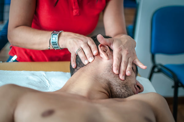 physiotherapist visits a young sportsman who feels pain at neck