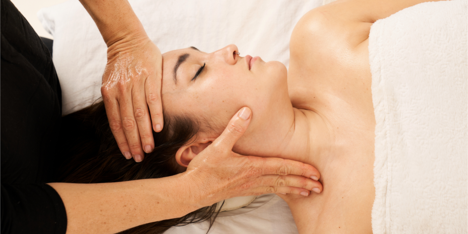 woman receiving a facial massage in the area of the cervicals