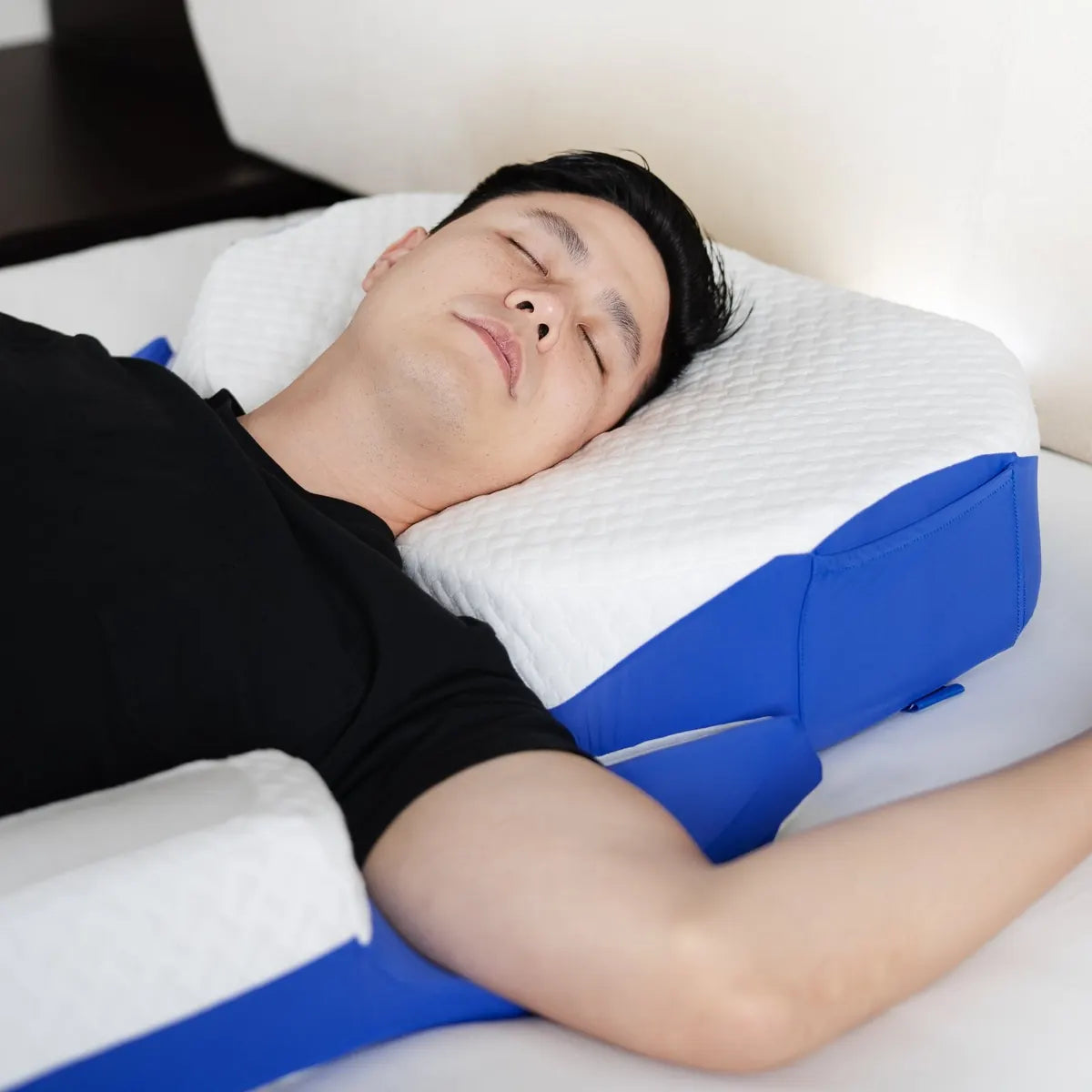 A man asleep on his side, his shoulder tucked into the cut-off corner of the octagon head pillow.